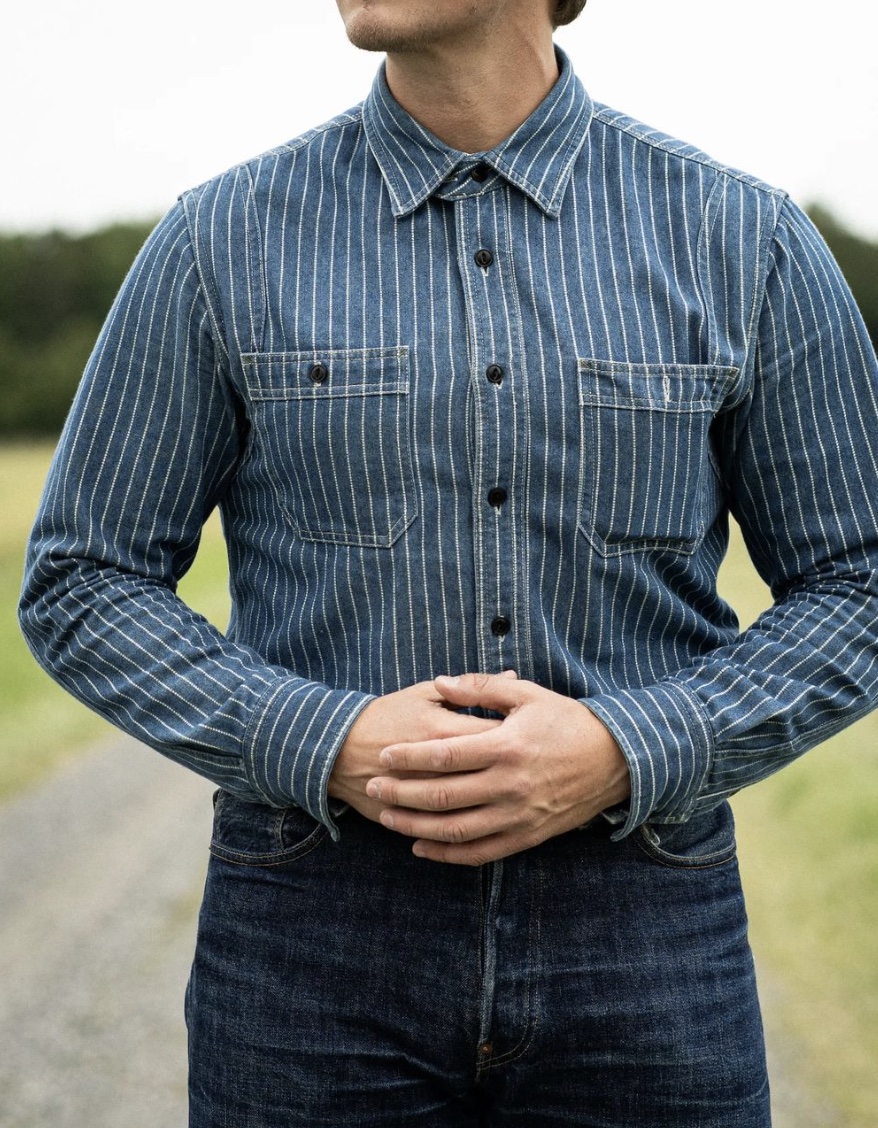 man holding hands together in front of his stomach wearing double blue denim