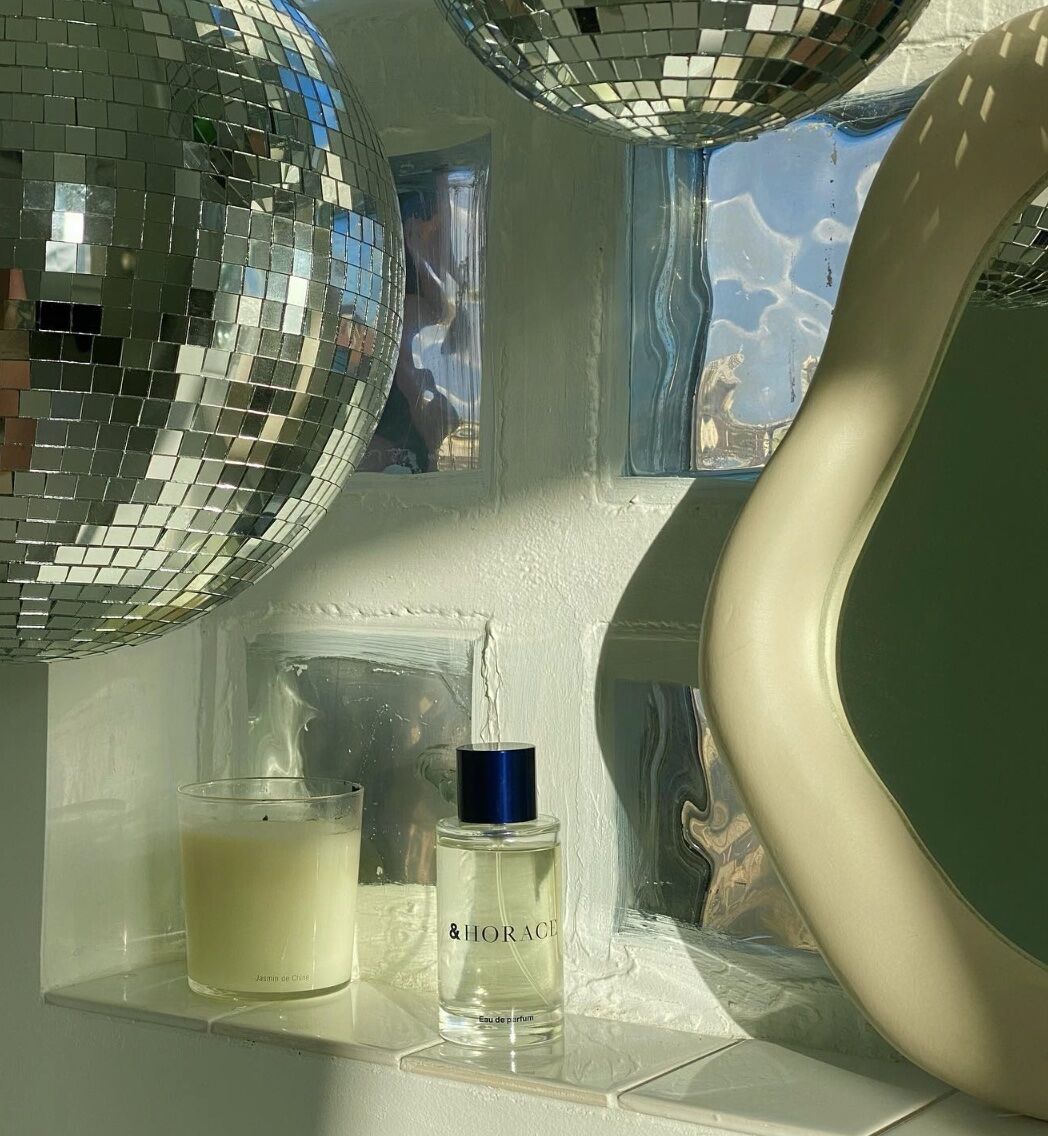 bottle of cologne on a shelf, disco balls and mirrors in background