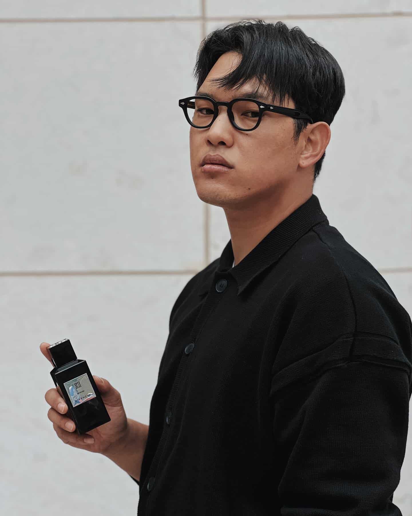 a man holding a bottle of givenchy perfume