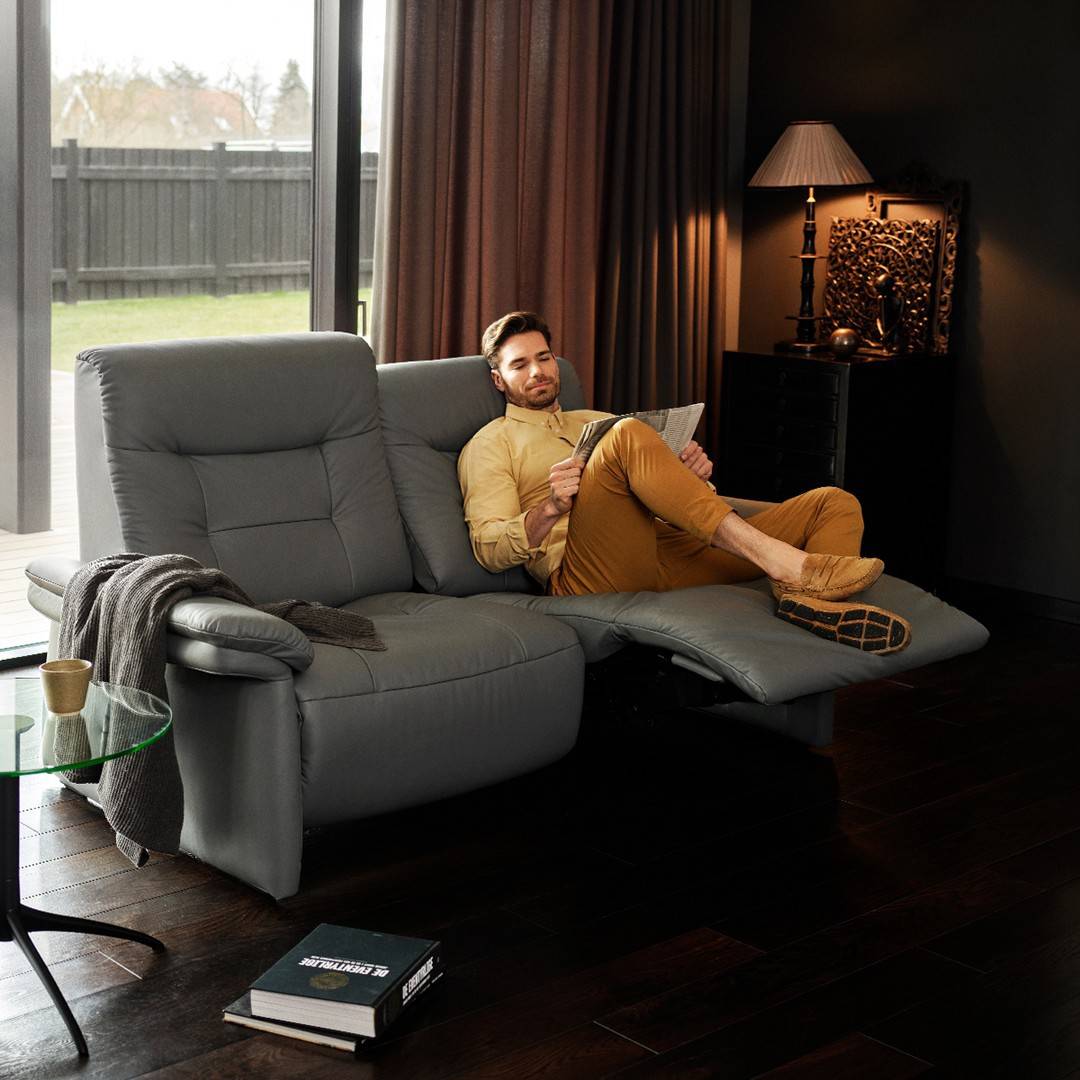 man reading a paper on a sofa recliner
