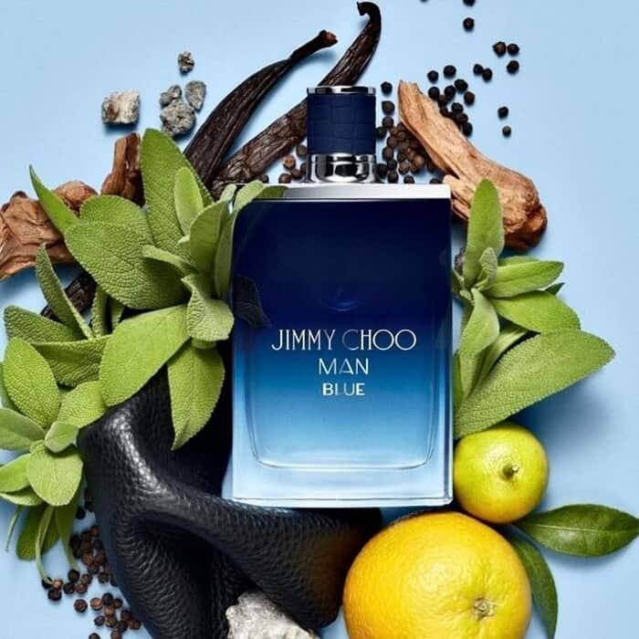 a bottle of jimmy choo man blue cologne surrounded by it's raw ingredients