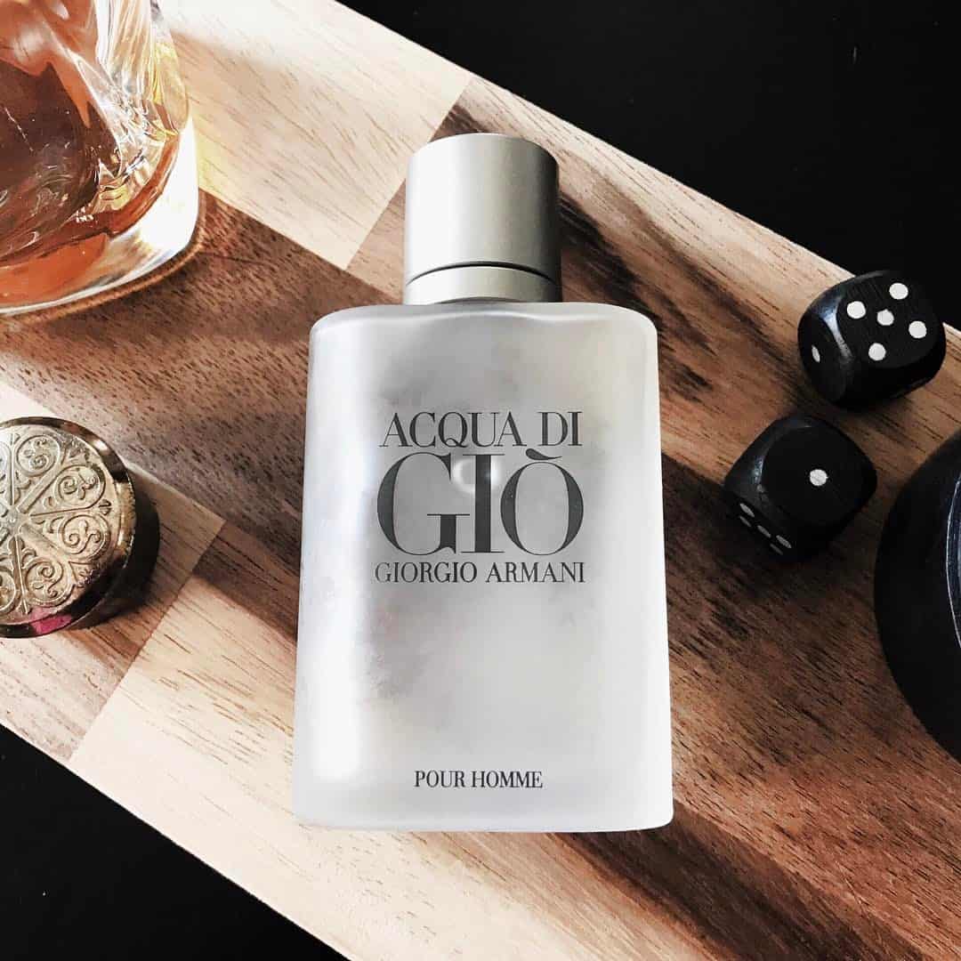 a pair of dice next to a bottle of acqua di gio pour homme